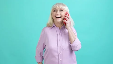 Positive aged lady answer friend call gadget isolated cyan color background Stock Footage 196147944