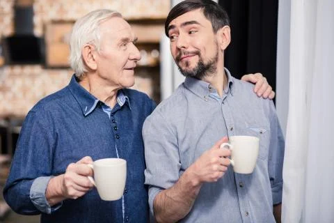 Positive aged man drinking tea with his son 스톡 사진