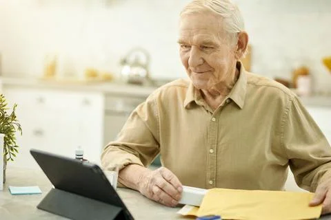 Positive aged man using tablet to contact his medical doctor Stock Photos