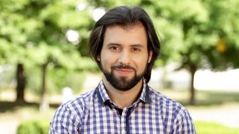 Positive and bearded man is looking on camera and smiling a bit. Then he starts Stock Footage 99740212