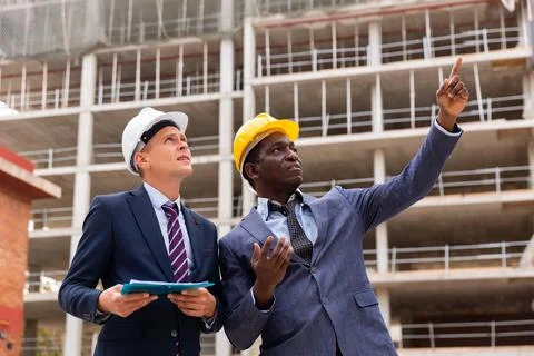 Positive architect and contractor having brief meeting on construction site Stock Photos