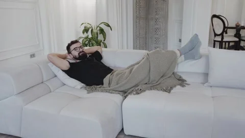 Positive bearded man resting with back on sofa in Stock Footage 259837695