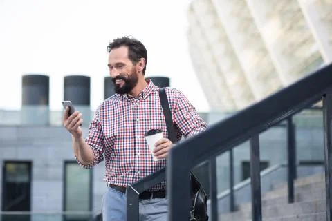 Positive bearded man using his phone outdoors Stock Photos
