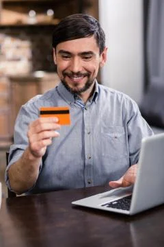 Positive bearded man using his credit card Stock Photos