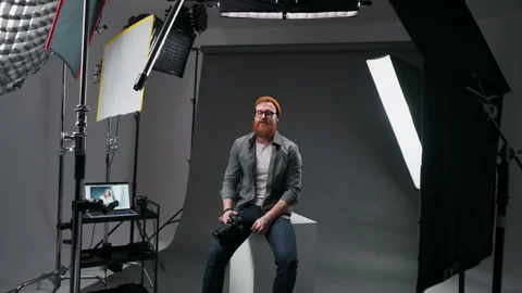Positive bearded photographer talking to camera in studio while making tutorial Stock Footage 263743464