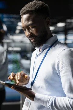 Positive black software developer doing maintenance tasks on tablet Stock Photos