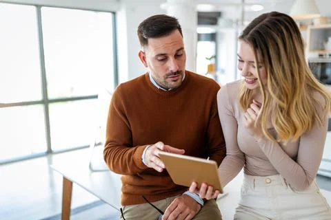 Positive couple having fun while working together remotely at home using modern Stock Photos