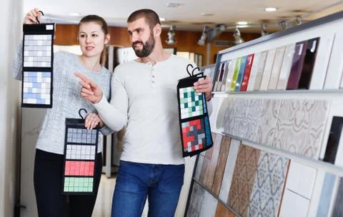 Positive couple holding sample of kitchen ceramic tile in modern store Stock Photos