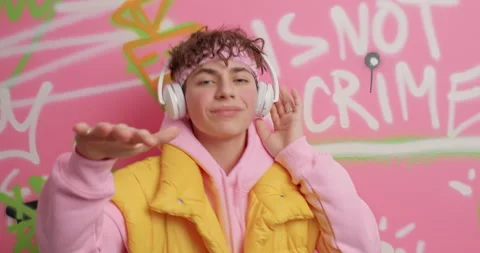 Positive curly handsome guy dances carefree listens music via stereo headphones Stock Footage 151194224