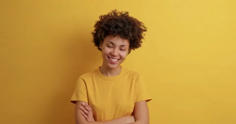 Positive dark skinned female model with Afro hair keeps arms folded smiles Stock Footage 149915725