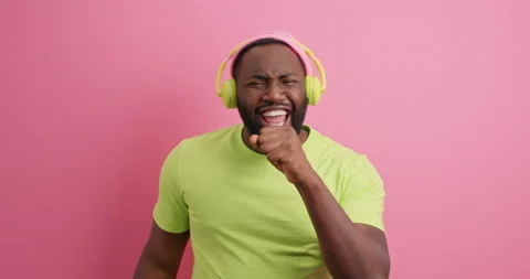 Positive dark skinned man dances carefree sings favorite song keeps hand near Stock Footage 150704235