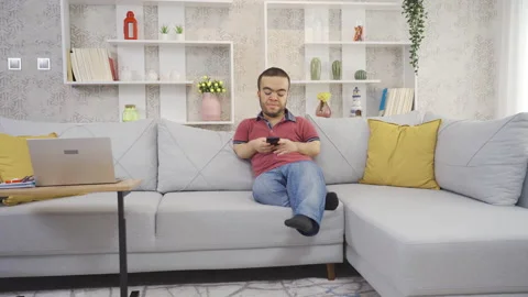 Positive disabled dwarf young man at home happily looking at phone  Video stock 230969722