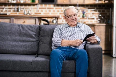 Positive elderly man reading an e book Stock Photos