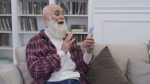 Positive elderly man talks to his family on video call via smartphone Stock Footage 226960720