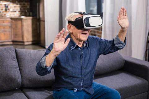 Positive elderly man testing VR goggles Stock Photos