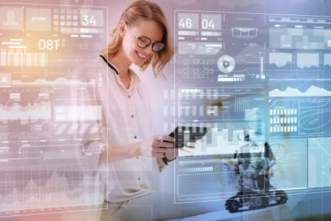 Positive engineer holding a modern tablet while testing a new robot Fotos de archivo