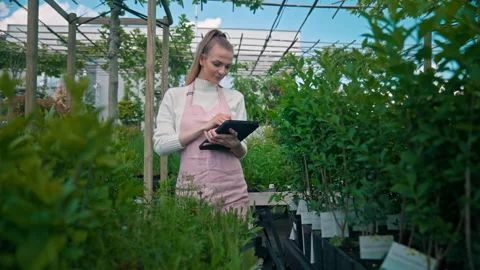 Positive female gardener using tablet computer, controlling cultivation system Stock Footage 201365365