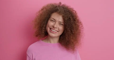 Positive good looking curly haired young woman with curly bushy hair waves hello Stock Footage 152532819