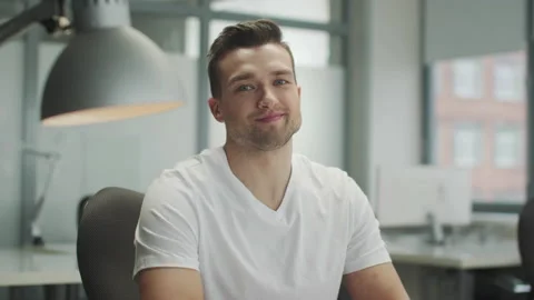 A positive, good-looking young man in the open office smiles while looking Stock Footage 152343881