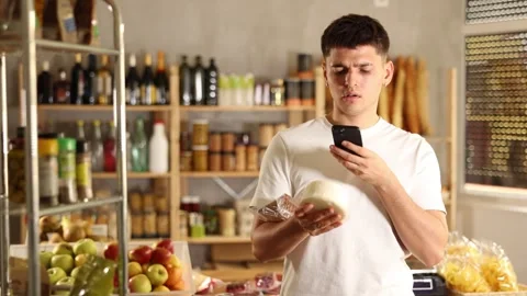 Positive guy purchaser scanning QR code or barcode of dried meat in supermarket Stock Footage 306983245