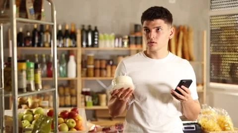 Positive guy purchaser scanning QR code or barcode of dried meat in supermarket Stock Footage 344837965