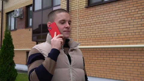 Positive guy with a red smartphone walks through the city and smiles. casual Stock Footage 288792248
