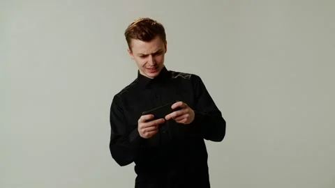A positive guy student uses a smartphone, plays games diligently and Stock Footage 253036196