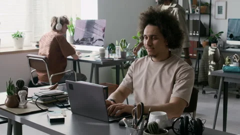 Positive Guy Typing on Laptop and Checking Phone Notification in Office Stock Footage 299206580