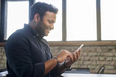 Positive indian guy using smartphone for online communication Stock Photos