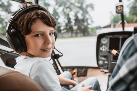 Positive kid in headsets entertaining in helicopter Stock Photos