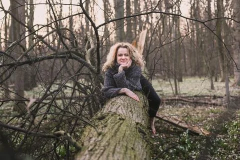 Positive lady resting on fallen tree scenic photography Stock Photos