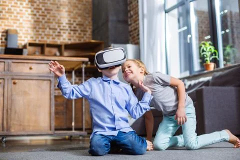Positive little boy testing VR device with his sister Stock Photos