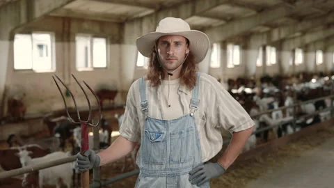 Positive man holding pitchfork while posing at goat farm Stock Footage 157585424