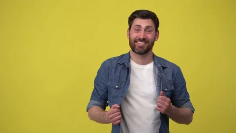 Positive man laughing at the camera spreading his arms on yellow background Stock Footage 188097217