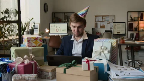 Positive Man Looking at Laptop Screen Working at Desk Cluttered with Gift Boxes 動画素材 331531475