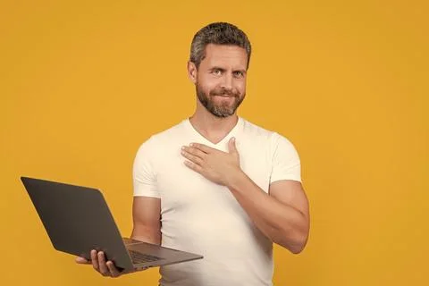 Positive man programmer with laptop isolated on yellow background. man Stock Photos
