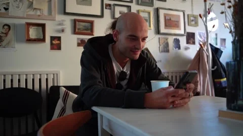 Positive man sitting in a cafe, looking at the phone Video stock 224331928