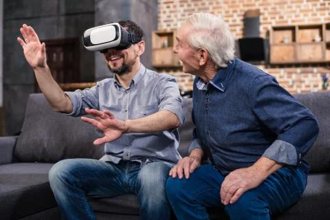 Positive man using VR device with his father Stock Photos
