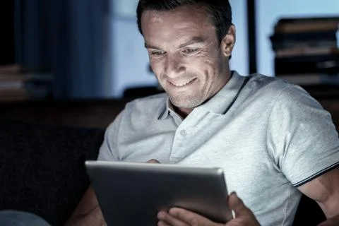 Positive minded man smiling while using tablet computer Stock Photos