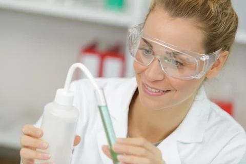 Positive minded woman smiling while looking at a test tube 写真素材