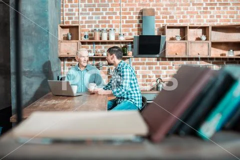 Positive nice father and son sitting in the kitchen Stock Photos