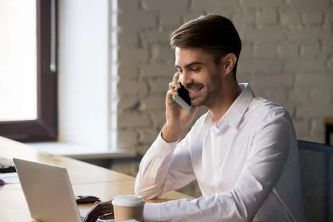 Positive office worker typing on computer talking on mobile phone Stock Photos