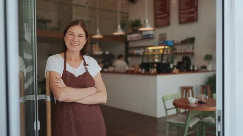 Positive old barista looking at camera and waving hand at entrance Stock Footage 238663583