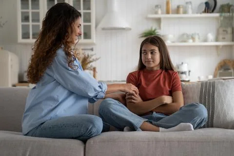 Positive parent mother cheering up sad teen girl daughter while sitting together Stock Photos