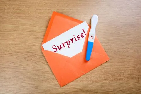 Positive pregnancy test in orange envelope on a wood background 스톡 사진