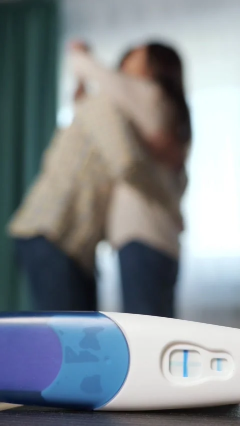 Positive pregnancy test with two lines in the foreground, focusing on the happy 库存影片 342907730