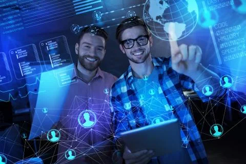 Positive programmers feeling glad while working with transparent screen Stock-Fotos