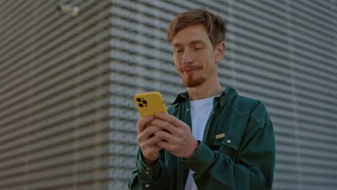 Positive redhead man using cell phone on street Stock Footage 162737211