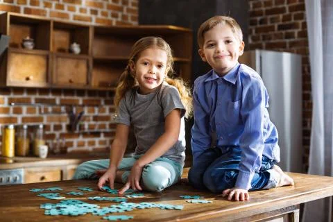 Positive siblings assembling jigsaw puzzles Stock Photos