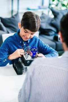 Positive smart boy constructing robot at home Stock Photos